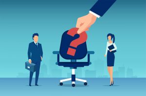 An illustration of a man and woman in business attire standing near an office chair with a large question mark on it, as a giant hand places the question mark, symbolizing job vacancy or recruitment.