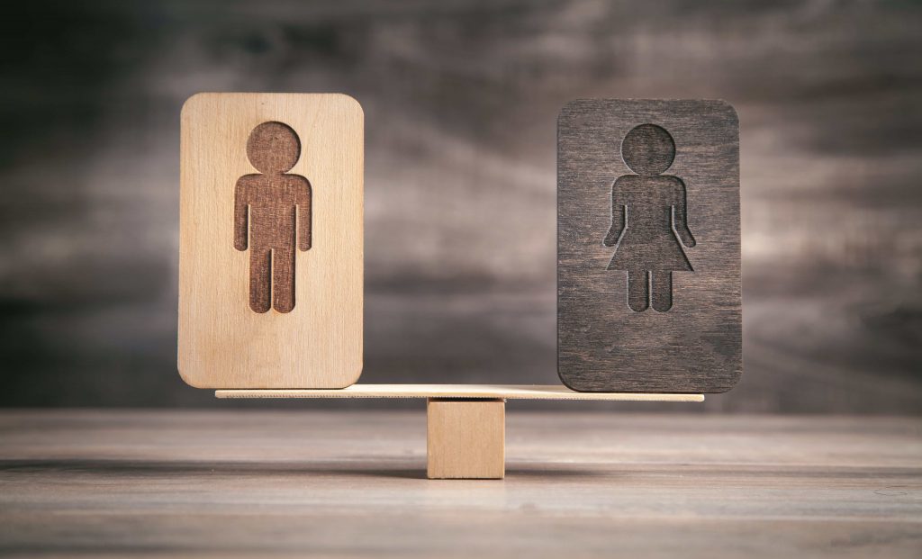 Male and female logos on a balance scale