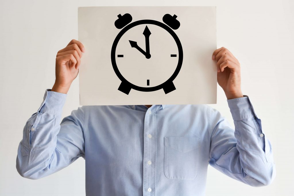 Man holding a picture of a clock in front of his face