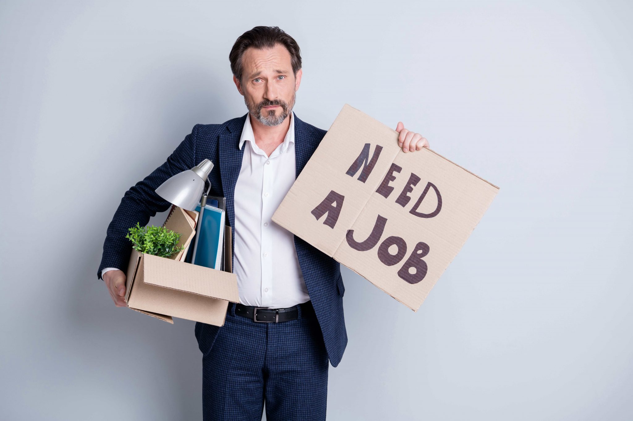 Older man holding up a sign that says "need a job"