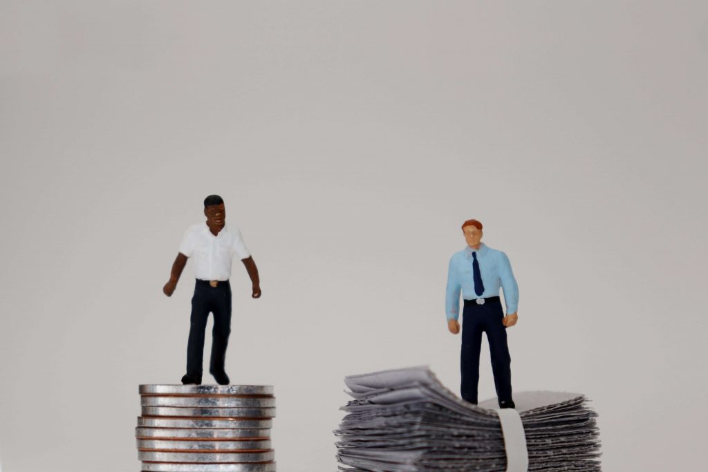 Illustration of an African American male standing on coins and a caucasian male standing on dollar bills