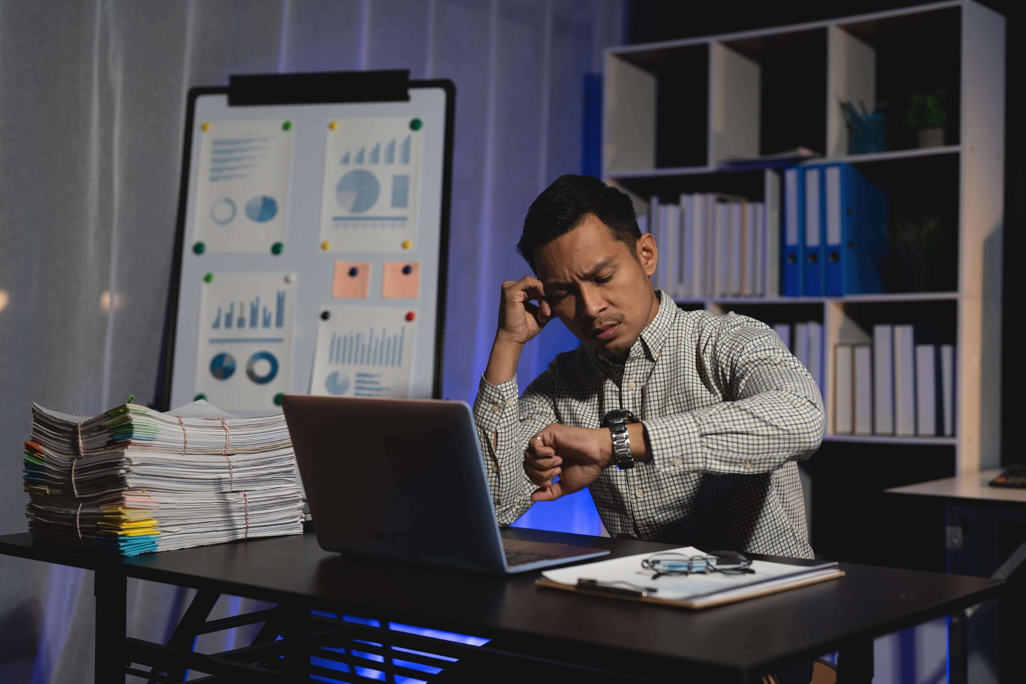 Worker looking at his watch as he works overtime unpaid