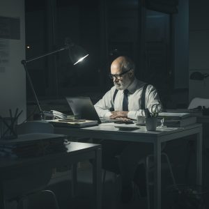 Corporate businessman working late at night in the office, he is connecting with his laptop