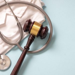 Health and Law. Medical malpractice, personal injury lawyer. Judge gavel, stethoscope and doctor coat, on blue background, top view