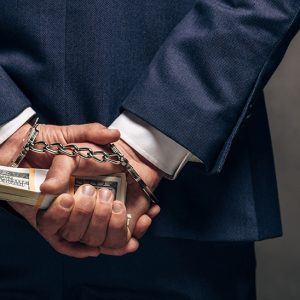 panoramic shot of handcuffed man holding bribe on grey